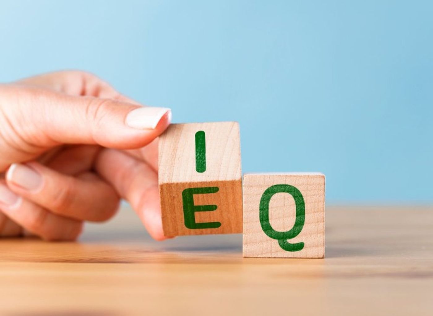 hand turning wooden lettered blocks E and Q that represent emotional intelligence