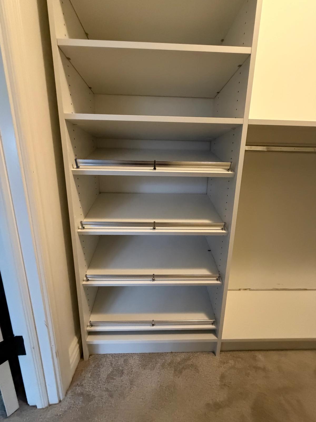 White closet with angled shoe shelves, metal shoe fences and a hanging section