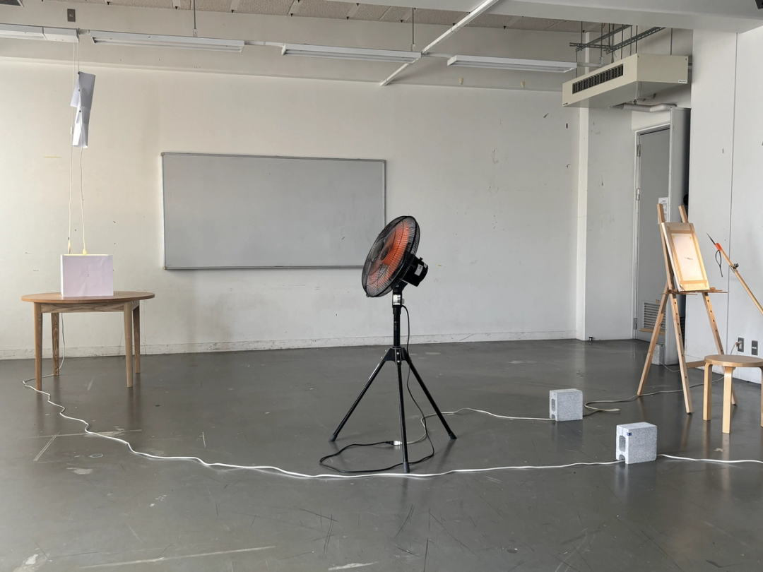 Electric fan, broom, easel, concrete block, string, pencils, table, light bulb, paper, peephole, extension cord, drawing machine