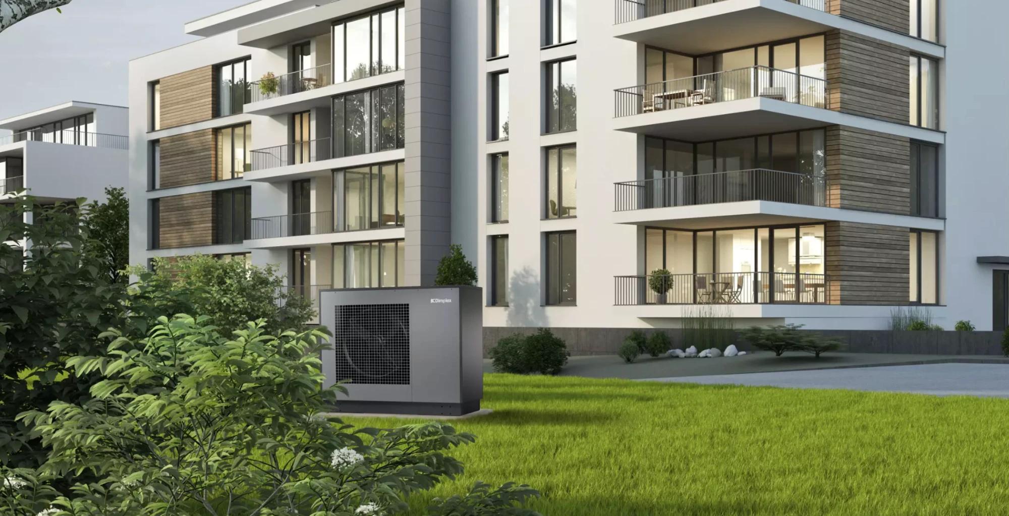 A Dimplex heat pump on the lawn outside a modern apartment building