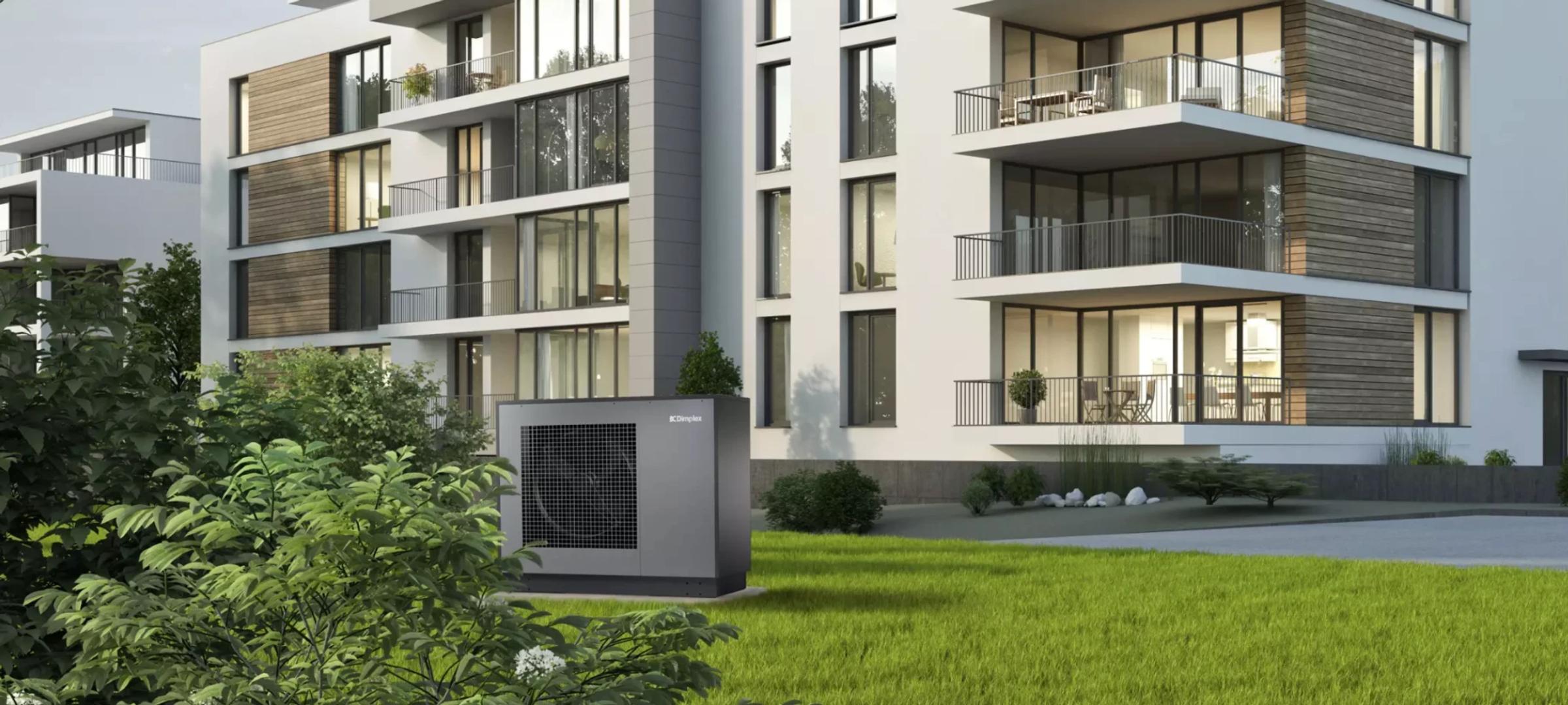 A Dimplex heat pump on the lawn outside a modern apartment building