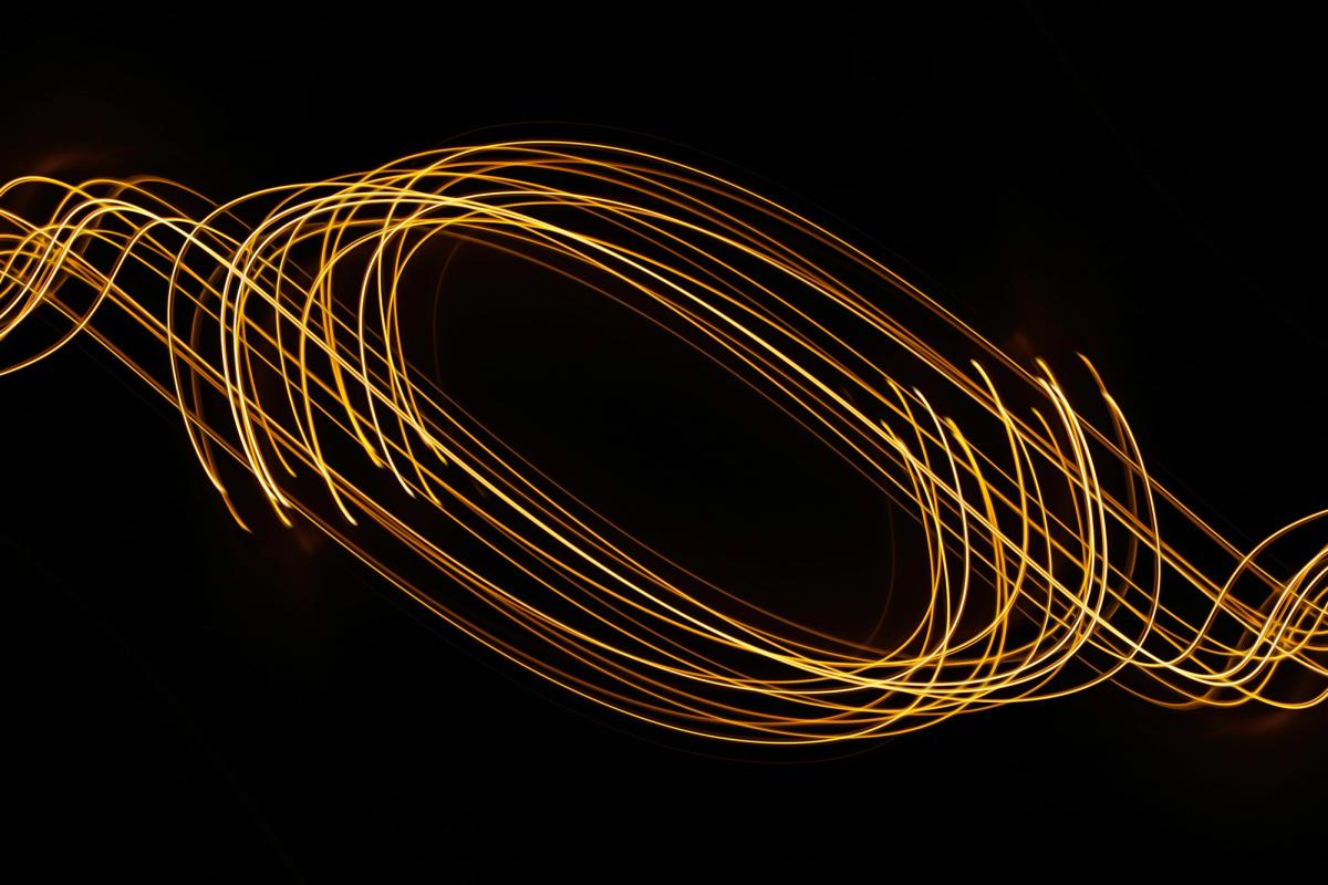 Streaks of light swirl around in unison against a dark background