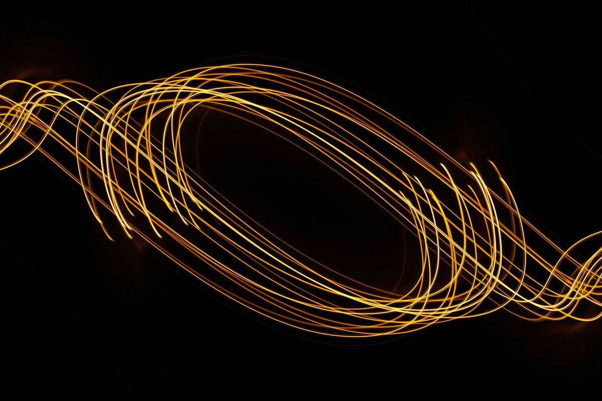 Streaks of light swirl around in unison against a dark background