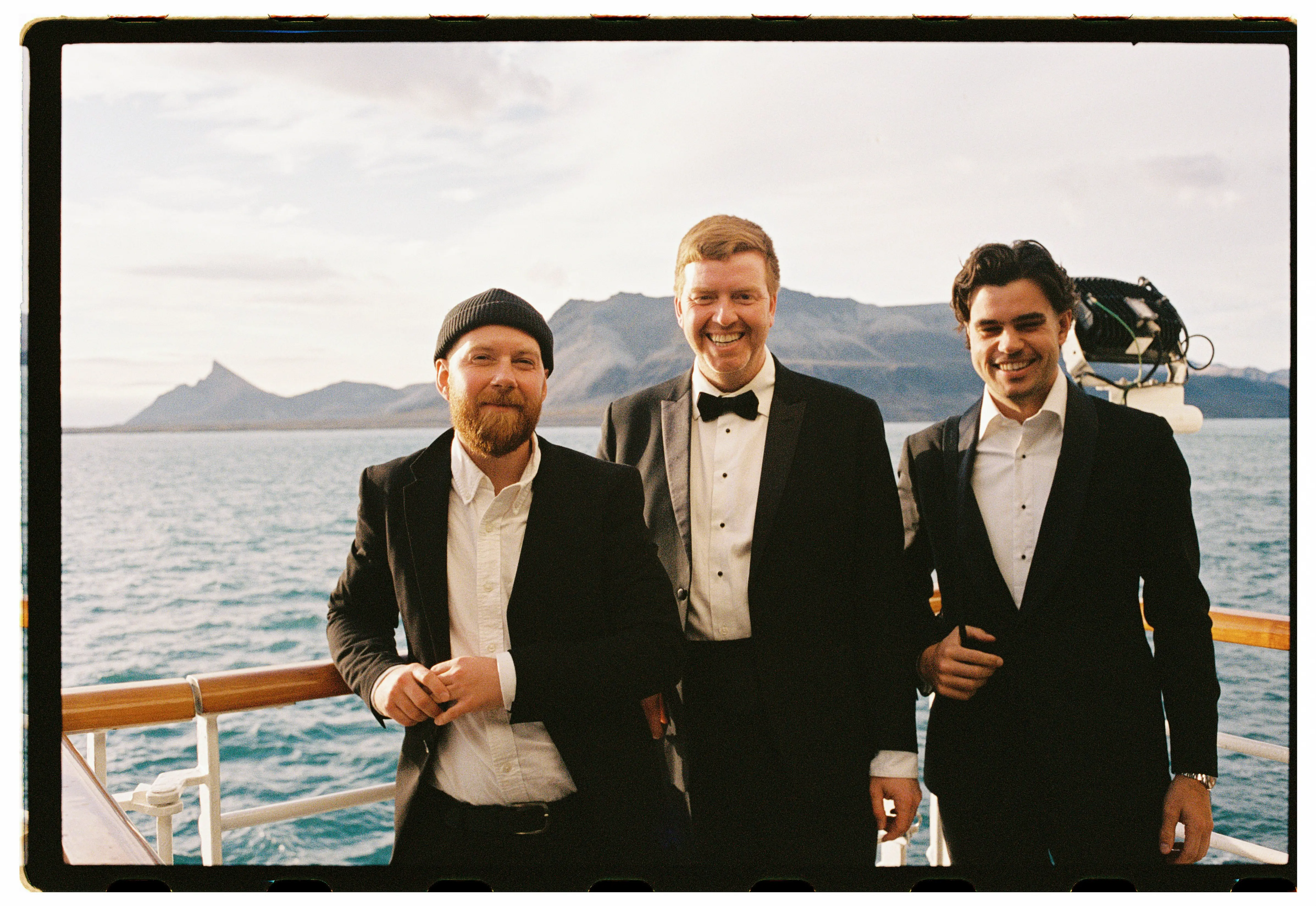 Alex Hillary and 2 friends wearing Tuxedos on a boat