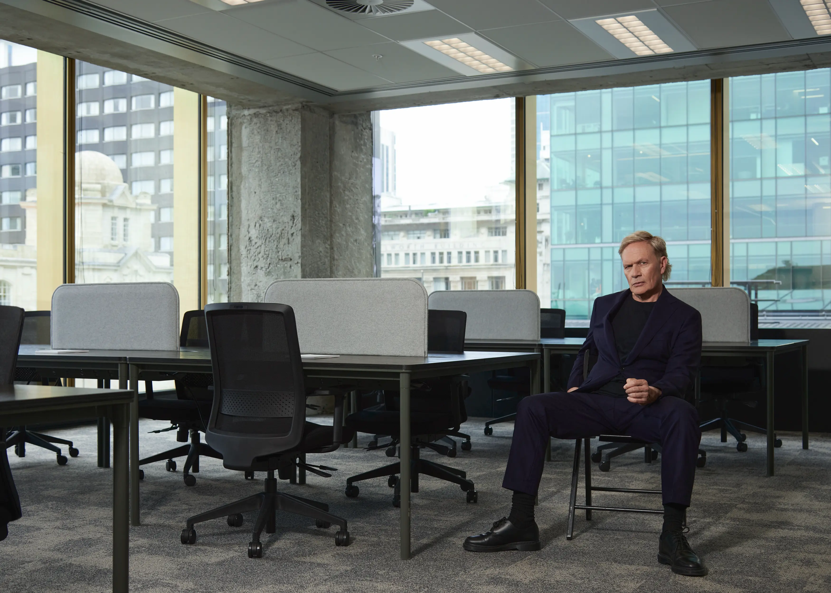 Shayne Carter Sitting on Chair in empty office space