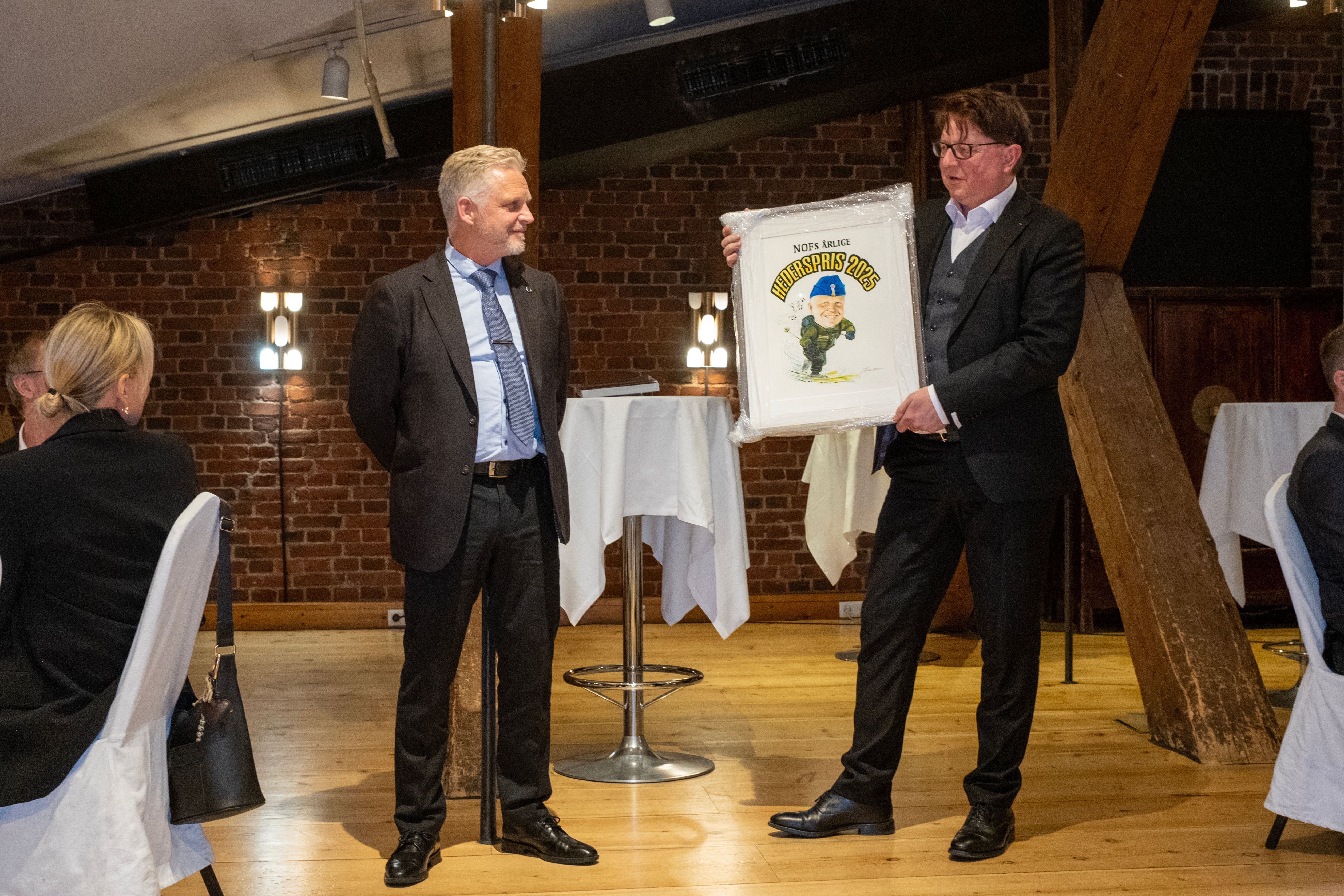 Jan Bendheim ble overakt NOFs hederspris for 2025 av forbundsleder Staale I Reiten. Prisen er tegnet av Arild Midthun som bla tegner Donald Duck. Foto: Torgrim Halvari