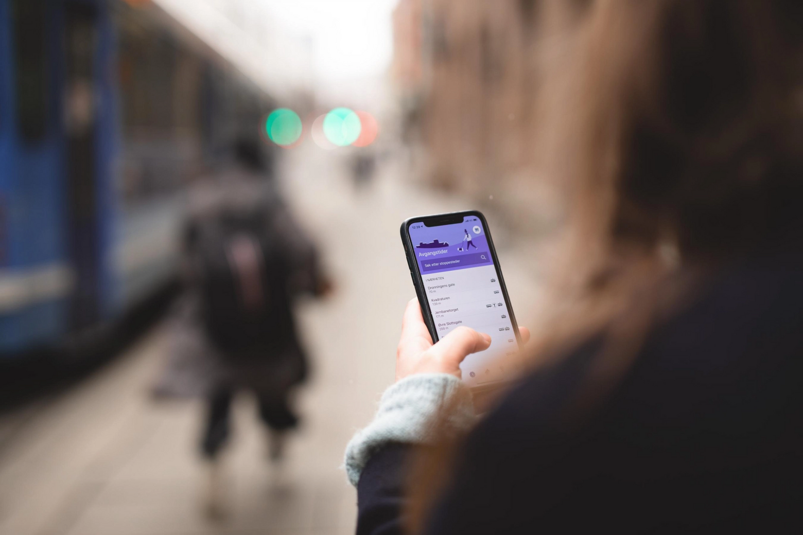 En dame holder en mobil som viser Ruter-appen