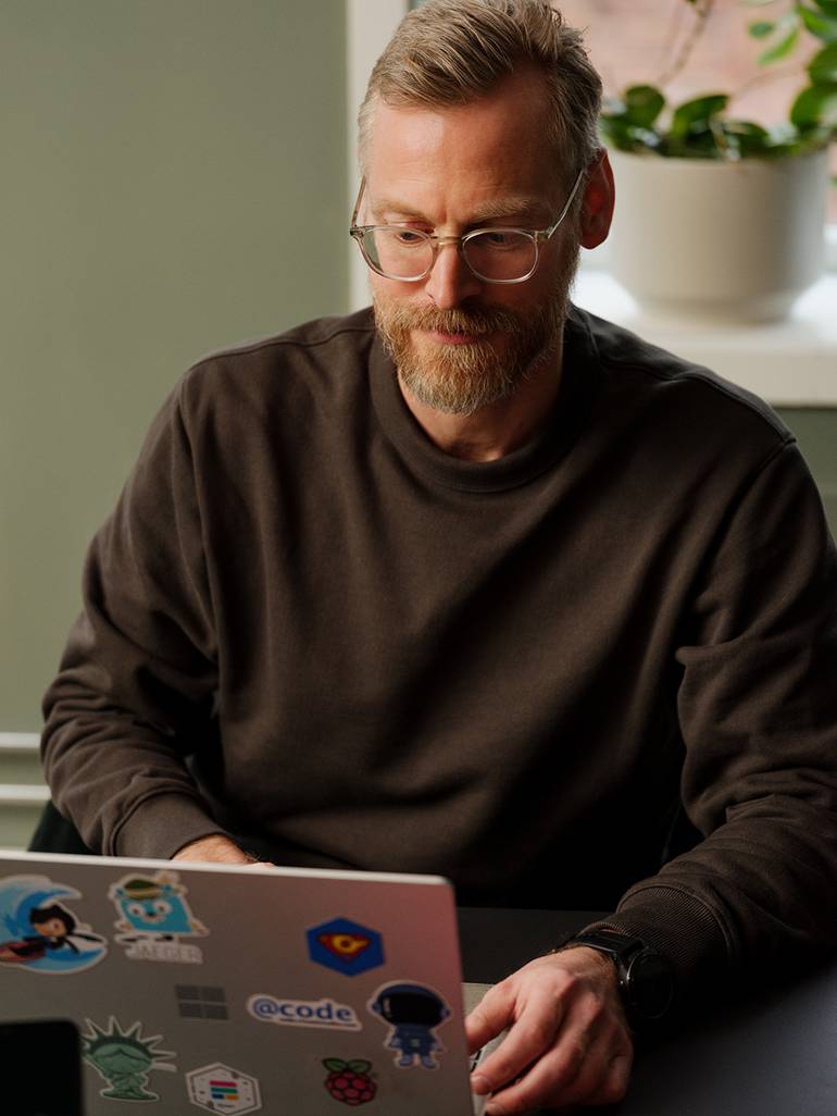 En mann sitter og skriver på en Mac