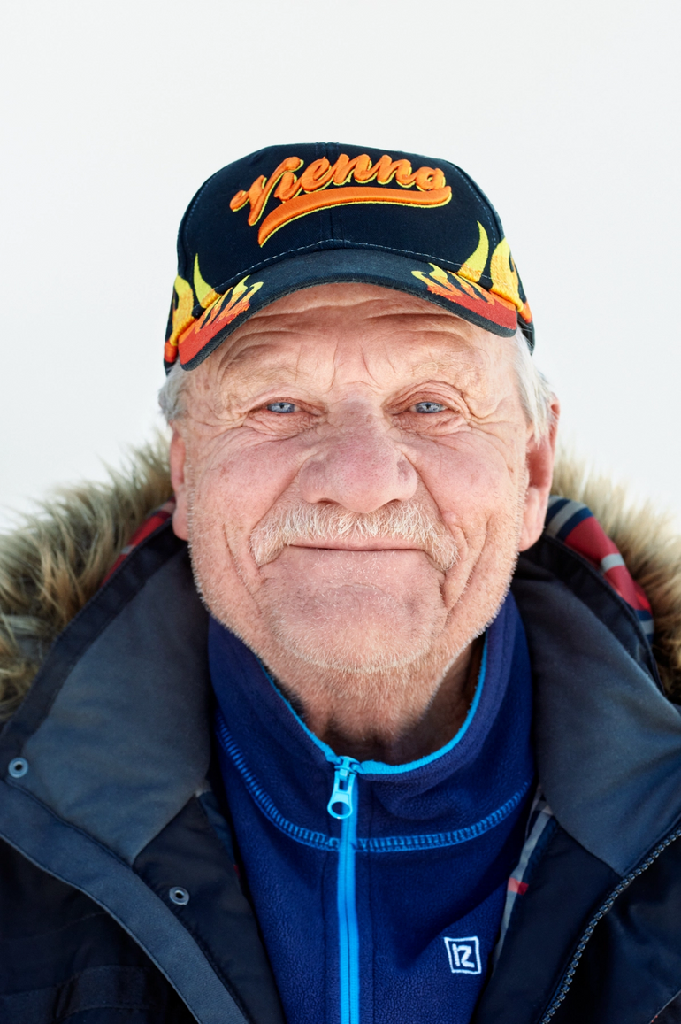 En eldre mann med caps som smiler