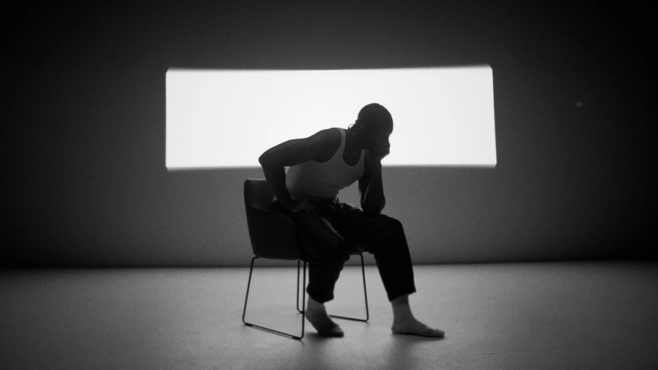 Patrik Kabongo seated in a studio chair under moody lighting in a stark frame from the “Dream” music video.