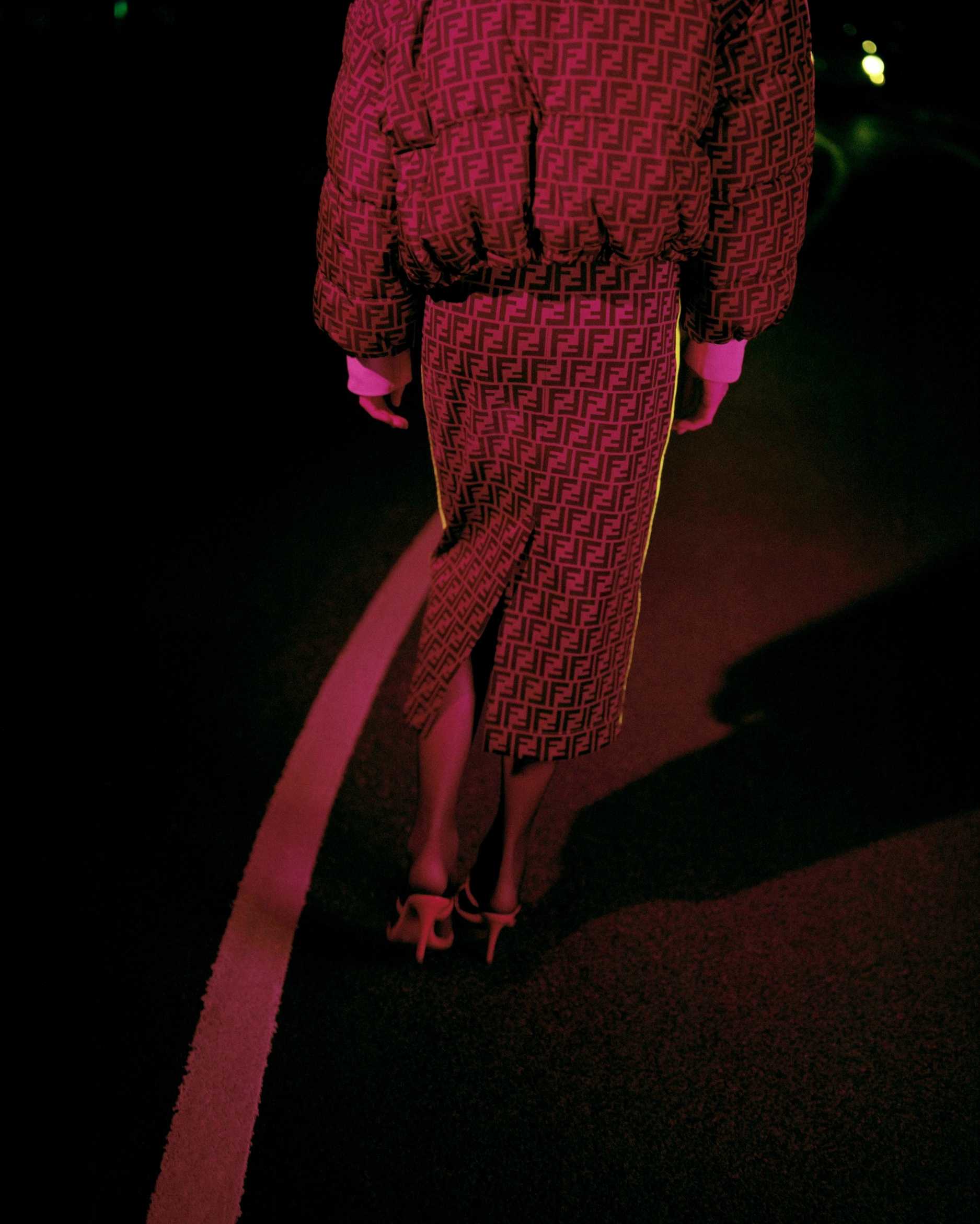 A woman wearing Fendi walks on the dark street