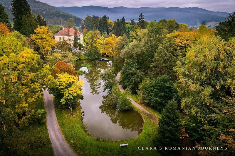 Aerial autumn view of the estate's pond and parkland with mountains beyond