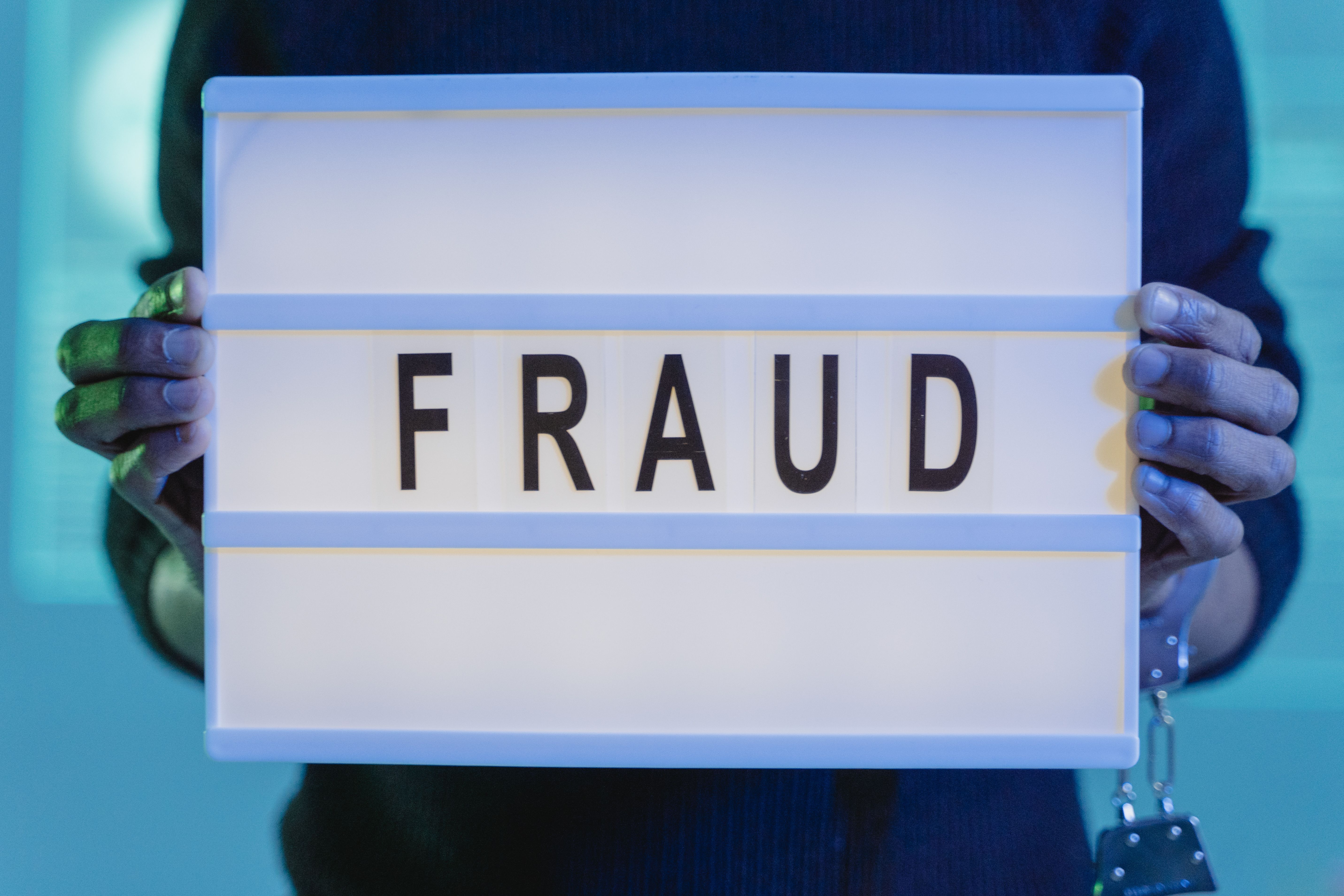 Person holding a lightbox sign that reads FRAUD, representing a New Jersey fraud investigation before charges are filed.