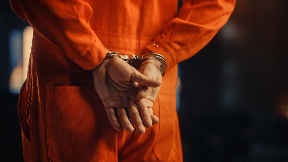 Image Close-up of a person in an orange jail jumpsuit with hands handcuffed behind their back, representing the severity of sexual assault charges in New Jersey.