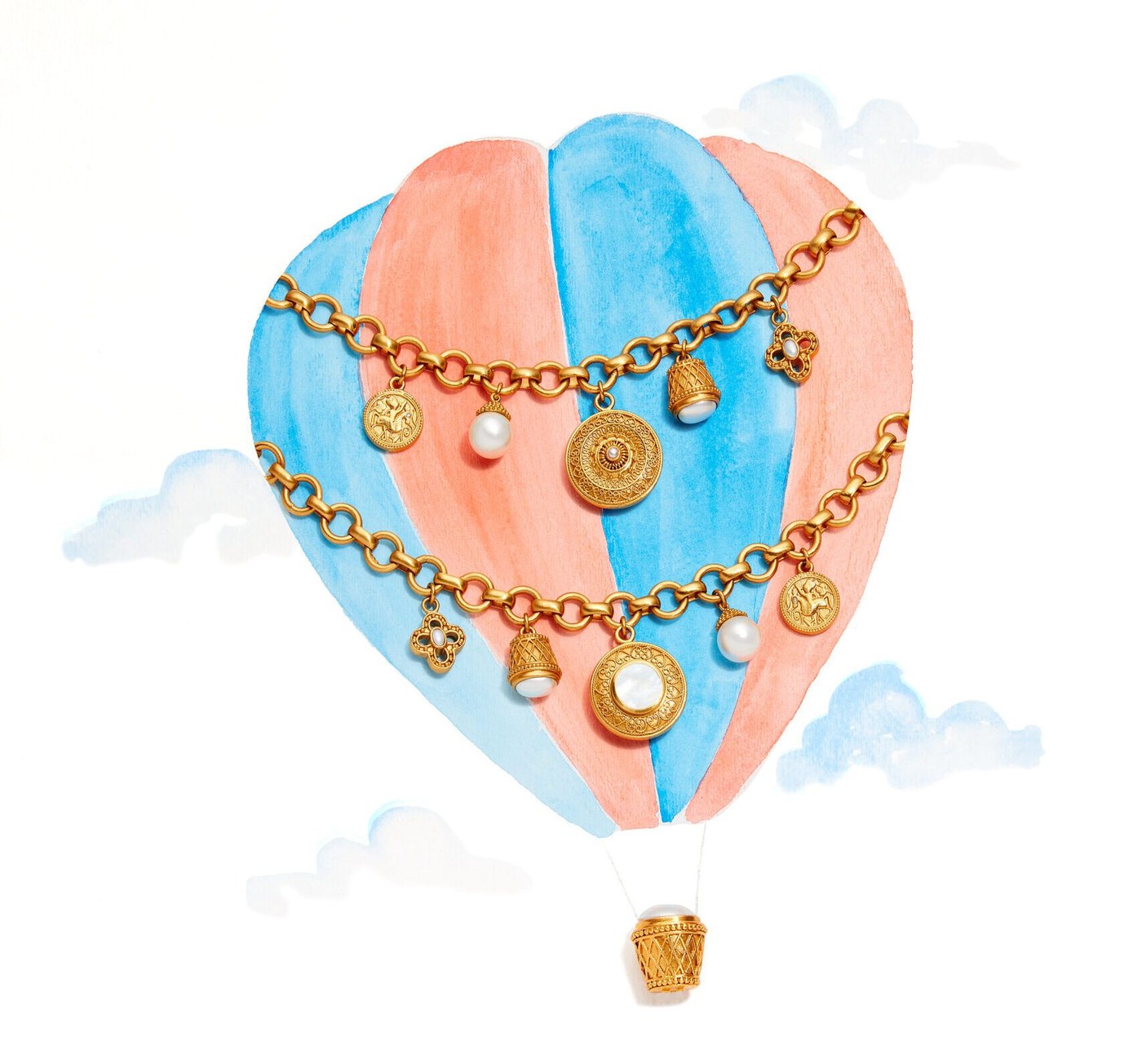 Gold charm jewelry draped over a painted pink-and-blue hot-air balloon