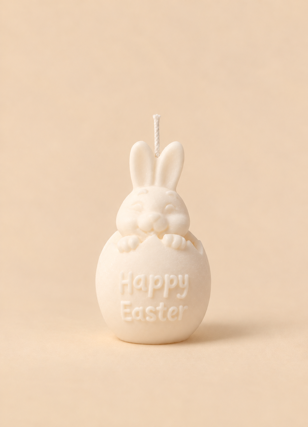 Vela em forma de ovo de Páscoa com orelhas de coelho e a mensagem Happy Easter