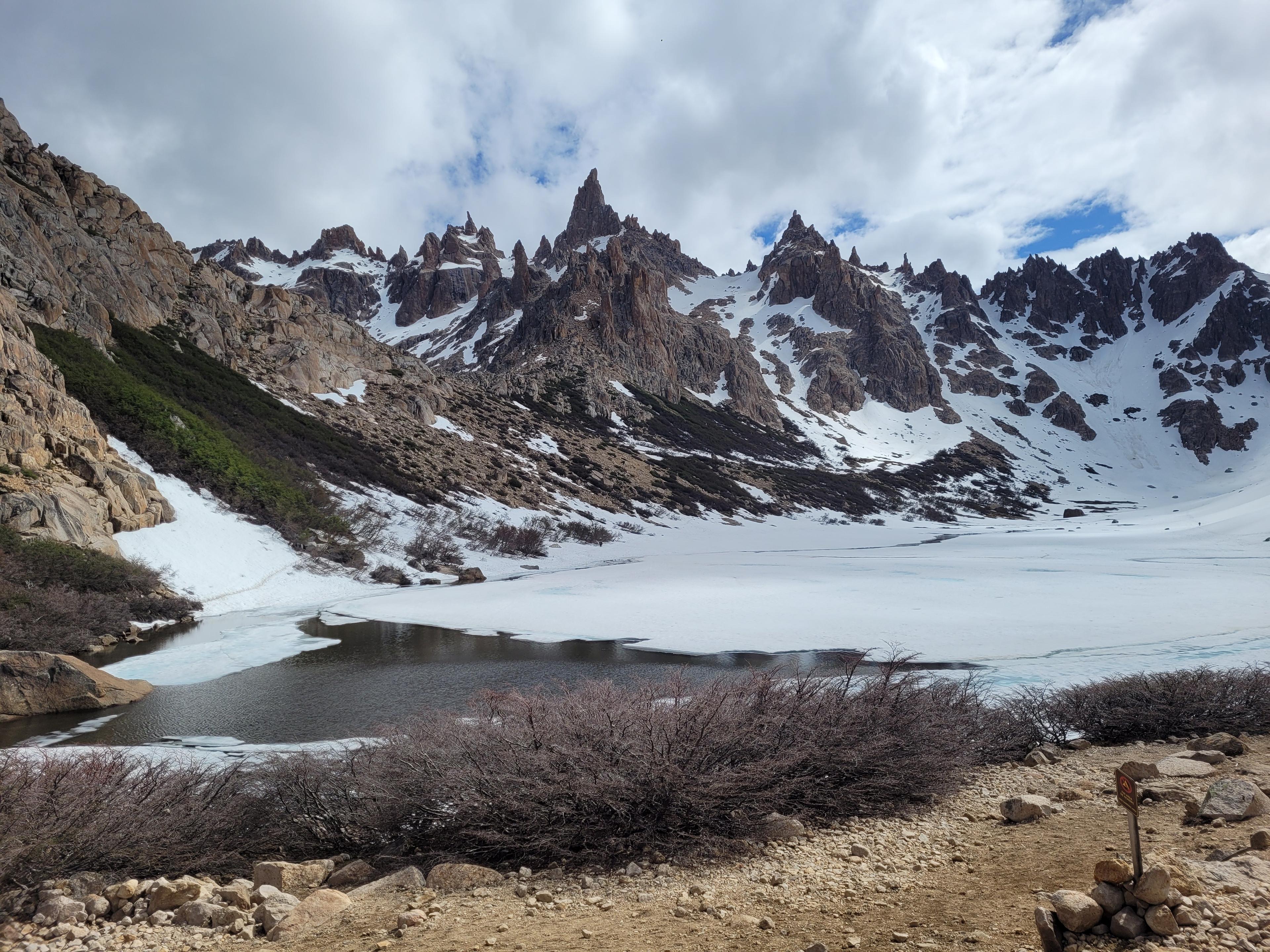 Laguna Toncek, parcialmente congelada, com picos nevados ao fundo