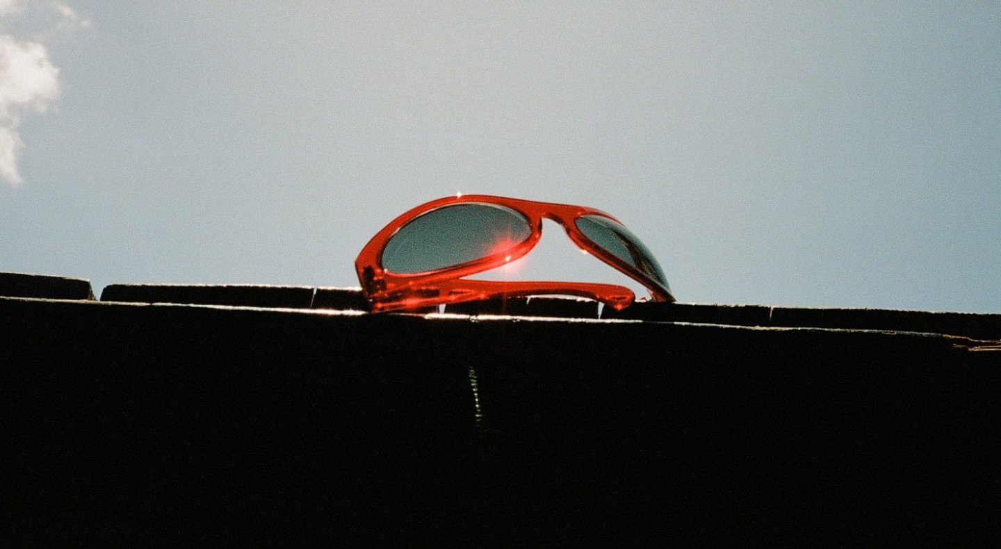 Red sunglasses on a wall under the sun