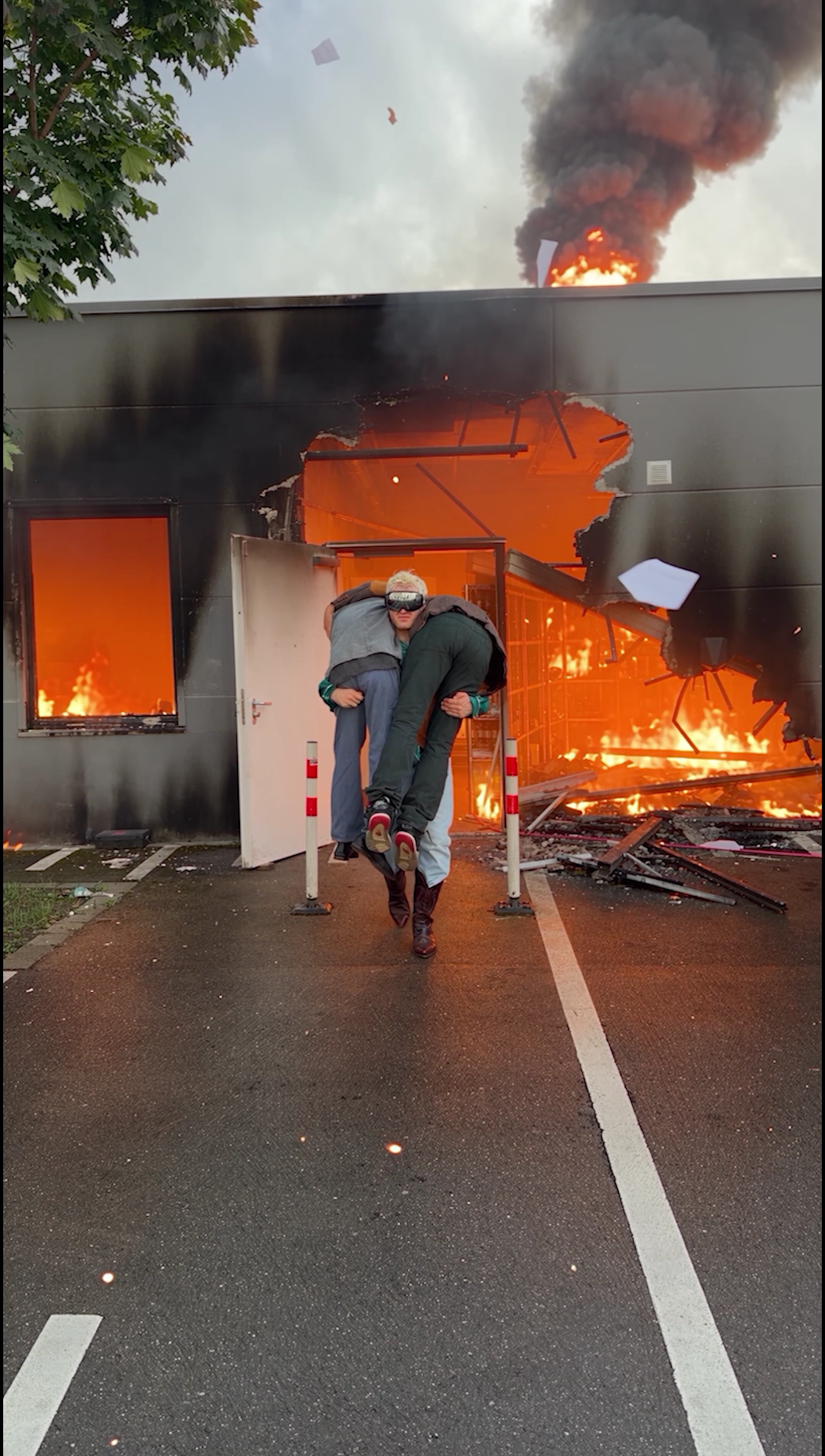 Ski Aggu carries two people out of a building with flames and smoke rising from its entrance in a Subway campaign still.
