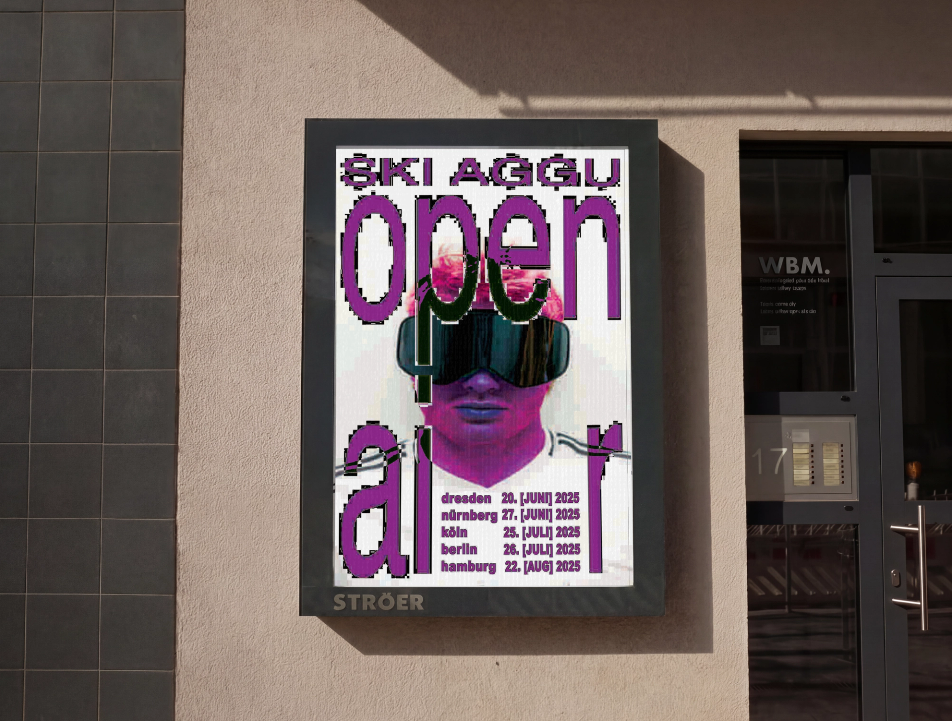 Poster in a display case on a house wall: "SKI AGGU open air" in distorted purple letters over a pink-tinted head in ski goggles, with five tour dates.