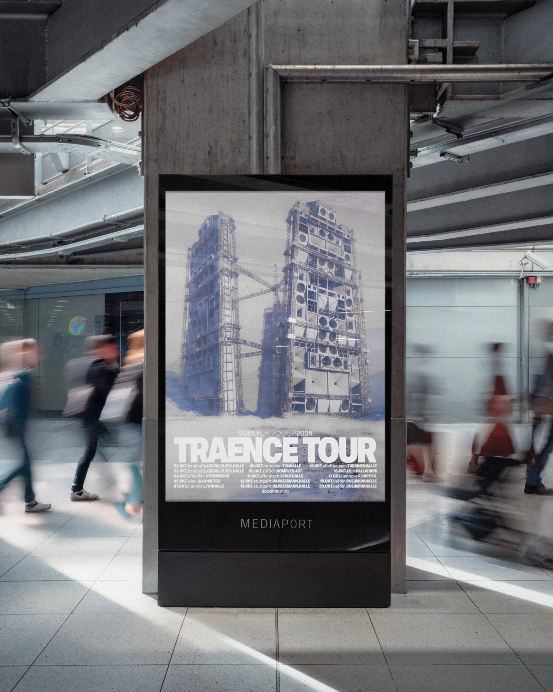 Souly's "TRAENCE TOUR" poster on a digital advertising screen in a station concourse, with blurred passers-by walking past.