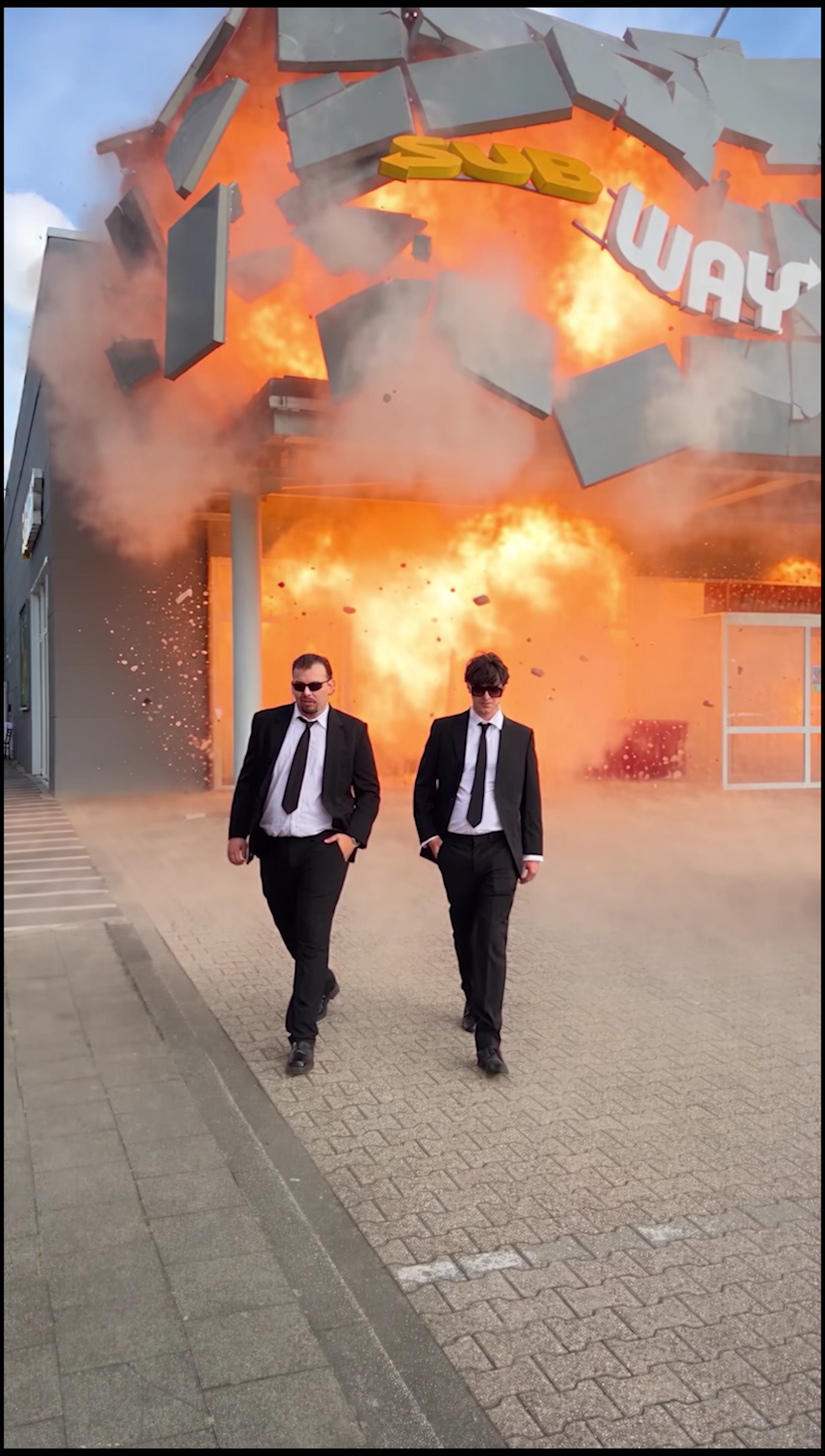 Two suited characters walk away from an exploding Subway restaurant in a campaign visual.