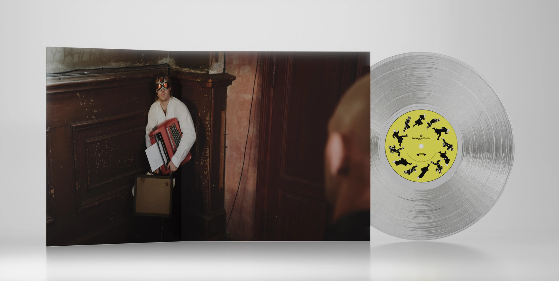 Transparent SkiAgguMusik vinyl with a yellow label beside a sleeve showing a performer holding an accordion.
