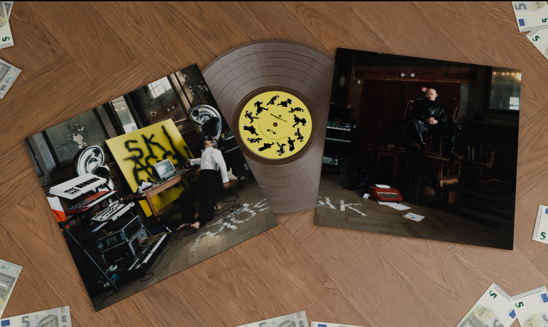 SkiAgguMusik record sleeves and a yellow-labelled vinyl arranged on a wooden floor with scattered banknotes.