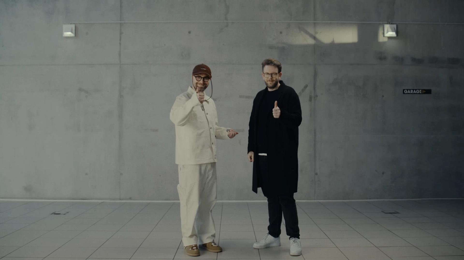 Mark Forster on the left in white and Jakob Lundt on the right in black, standing in a bare concrete room in the Schwarzer Toyota music video.