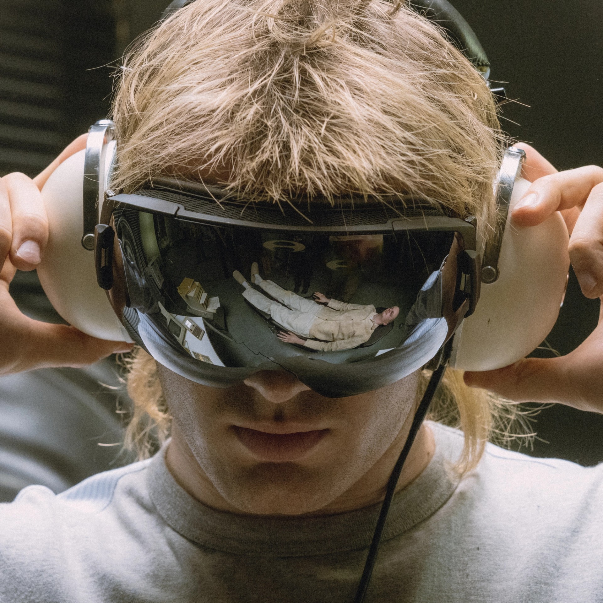 Close-up campaign portrait of Ski Aggu wearing mirrored goggles and large over-ear headphones.