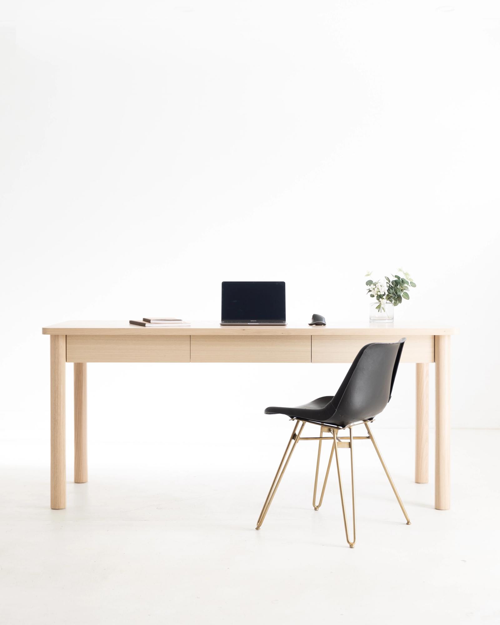 Abisko Study Desk in American Oak styled as a workspace with an office chair, three-quarter view showing the single drawer and tapered dowel legs