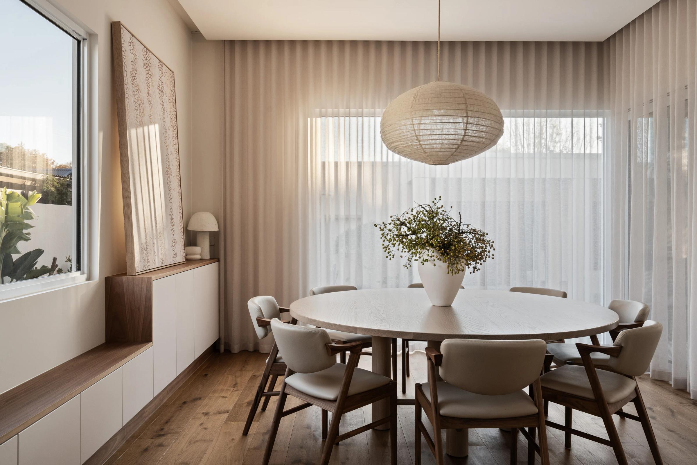 Odessa round dining table in American Oak, in a sunlit dining room with cream chairs