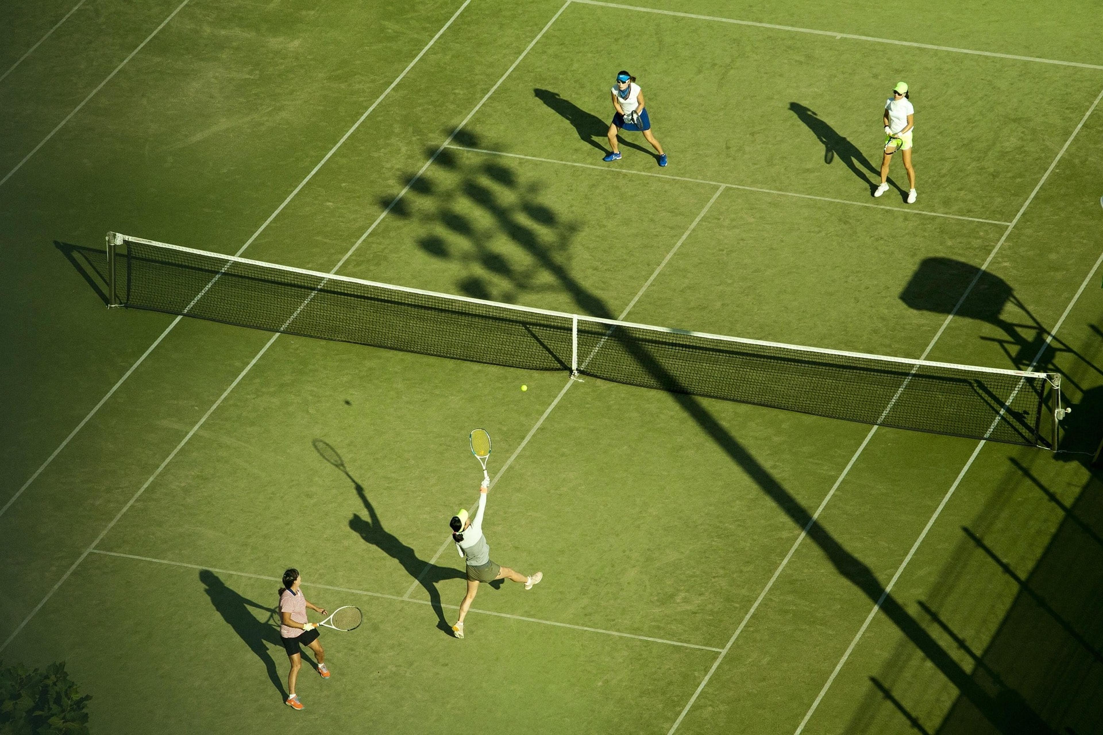 People playing doubles on grass court with tennis tactics