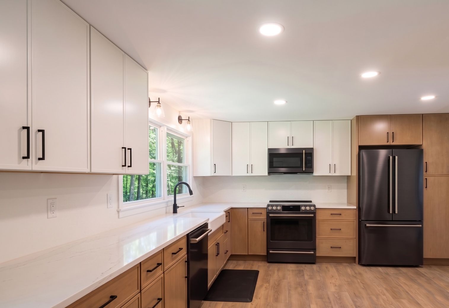 Completed kitchen renovation with two-tone cabinetry and black appliances