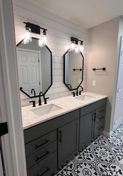 Renovated double vanity with dark cabinets and patterned tile flooring