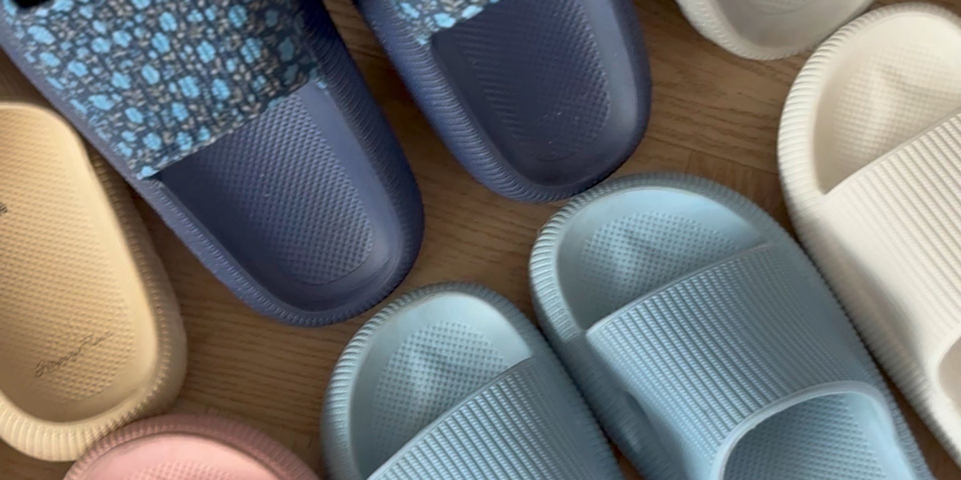 HappyFlops-slides in verschillende kleuren naast elkaar op een houten vloer