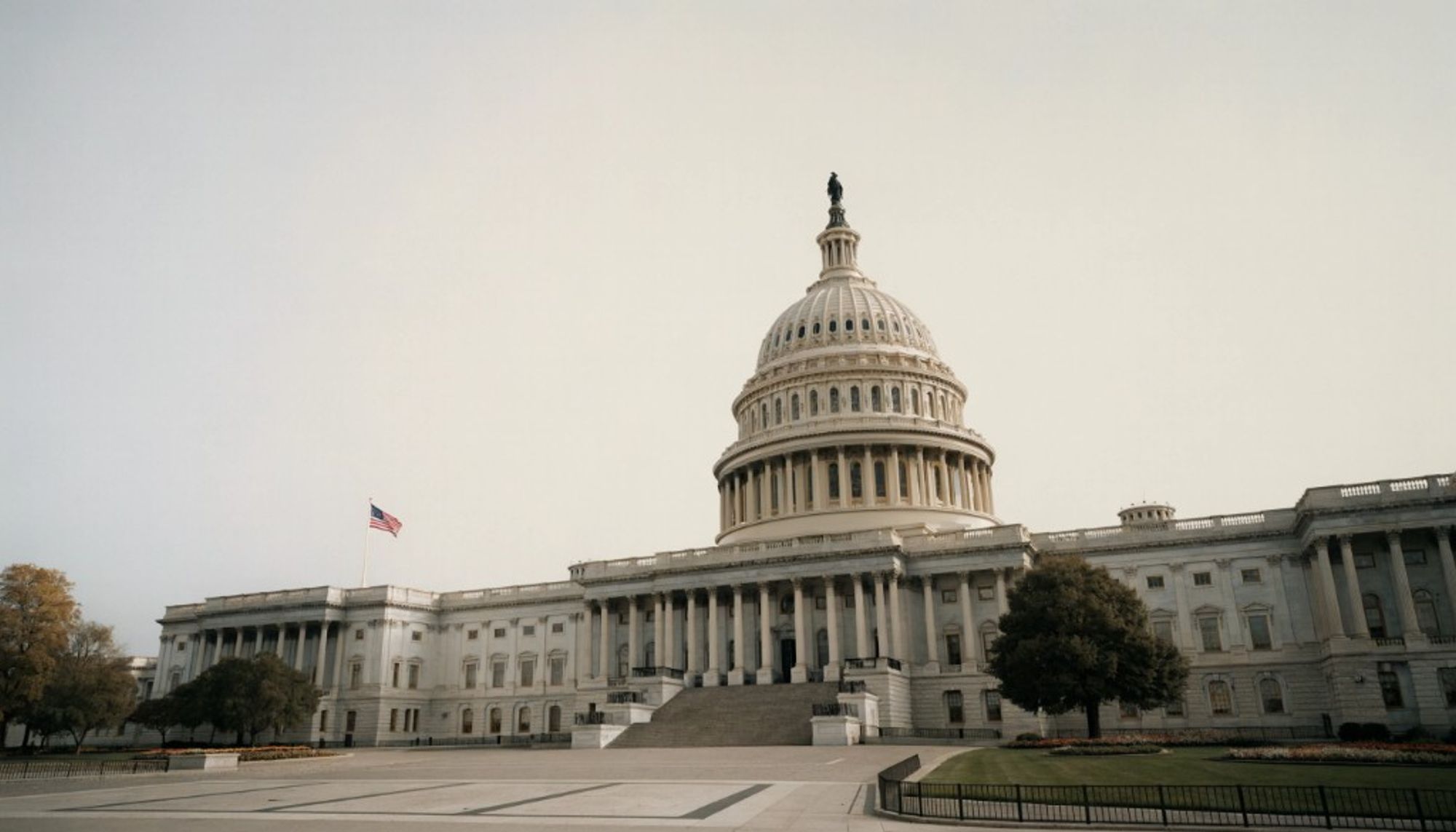 The white dome and columned front of the U.S. Capitol, with an American flag flying to the left