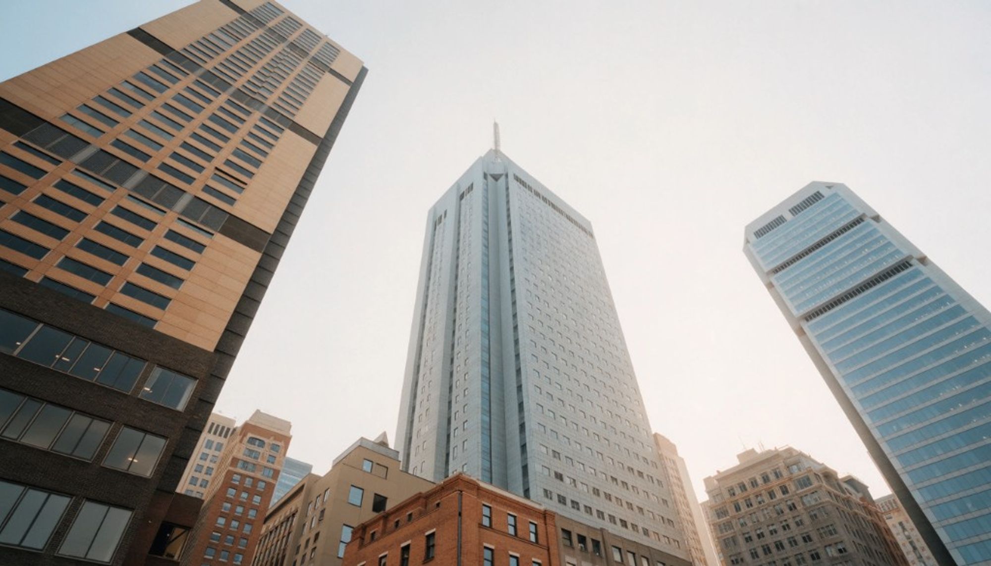 Looking straight up at glass and stone office towers in a downtown business district