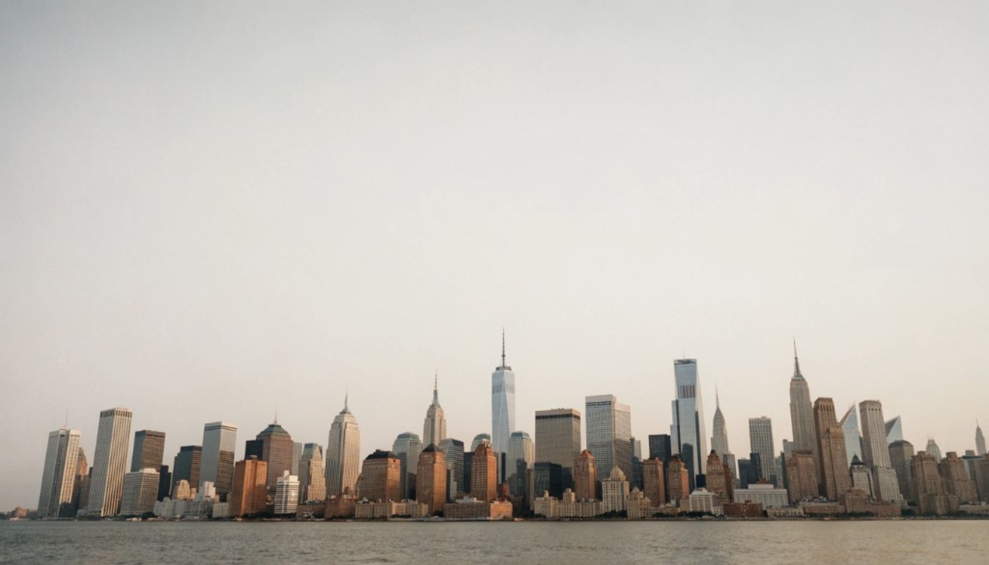 The Manhattan skyline seen across the water under a hazy sky