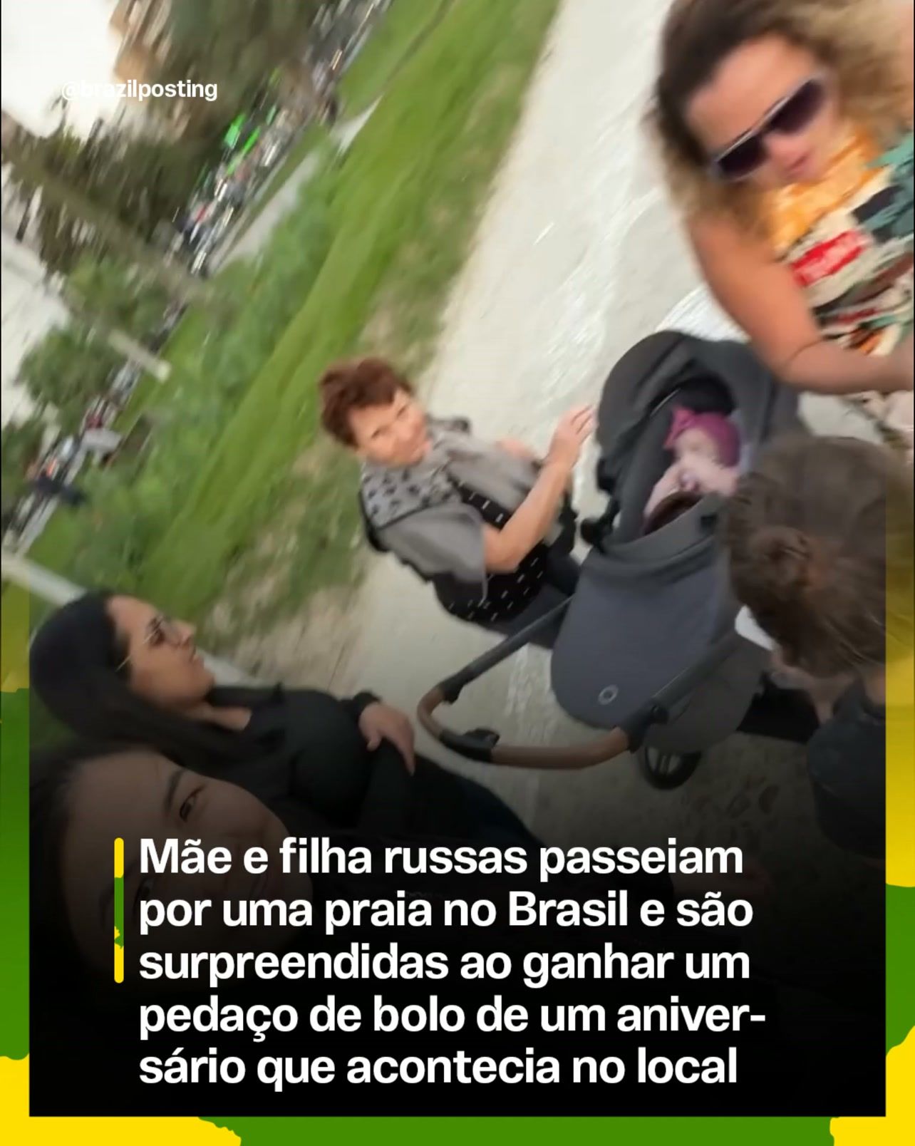 Mulher de óculos escuros e roupa clara em primeiro plano observa cena de grupo reunido em praia com grama ao fundo; crianças e outras pessoas participam do momento.