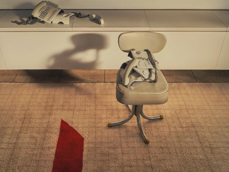 LIN-0244 rug on office floor underneath chair with pile of vintage phones