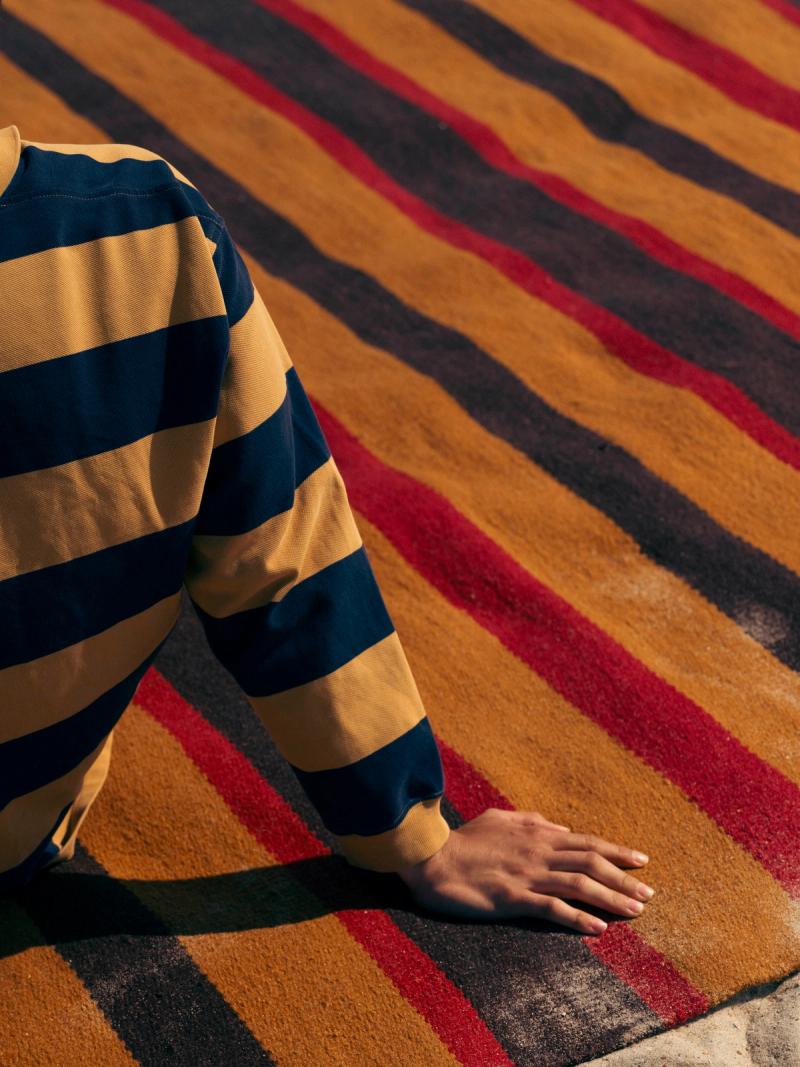 Male figure in striped shirt on striped rug