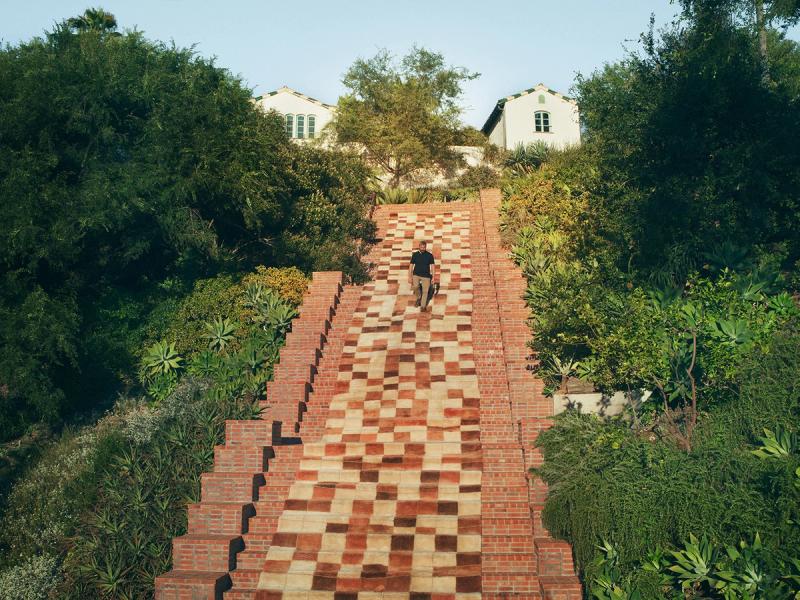 Bathhouse rug down estate staircase with man. 