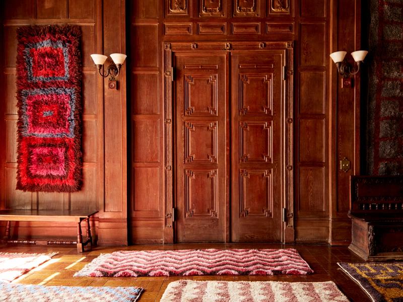 Mixed rugs hanging on wall and on floor. 