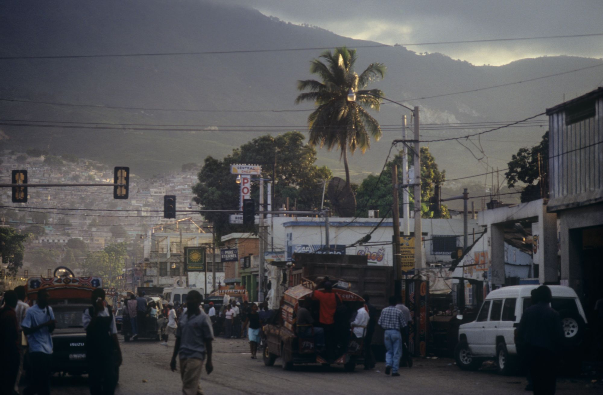 Hazy view down a busy street, with the hills rising in the background.