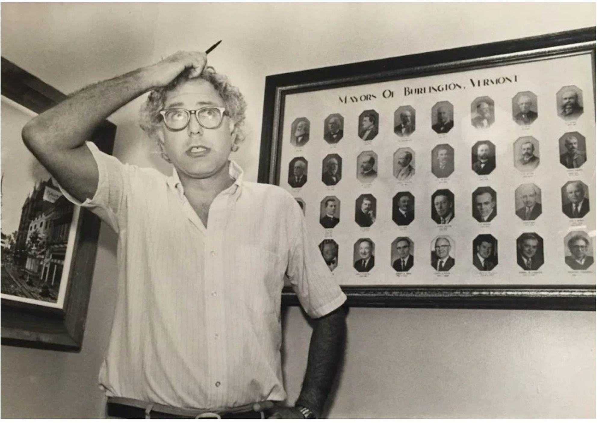 A bored Bernie Sanders sits with his chin in his right hand, looking around the Vermont legislature.  