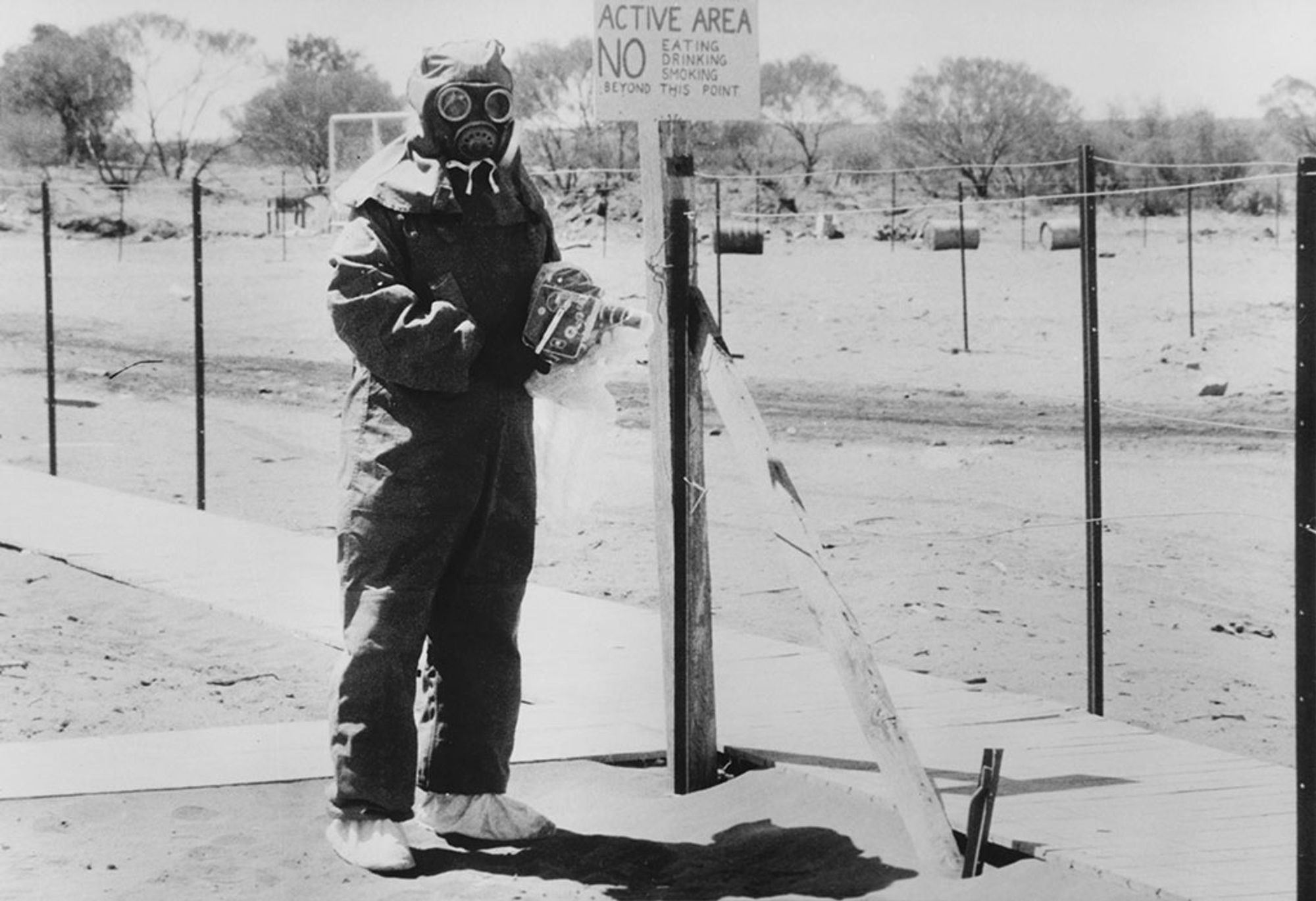 John L Stanier at Maralinga, Australia in protective clothing with a camera protected in a special plastic cover.