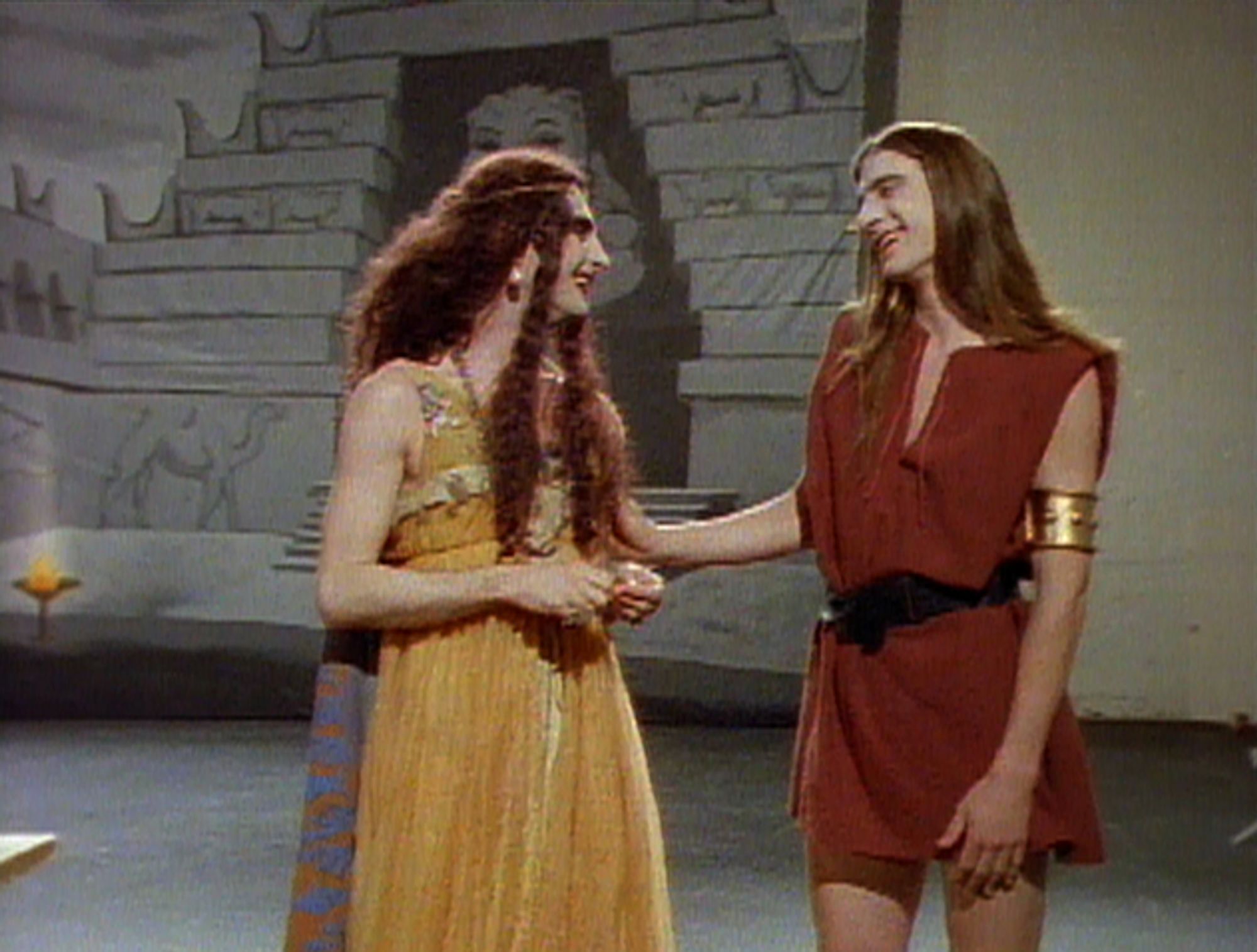 Two drag queens playing Biblical figures converse with one another.
