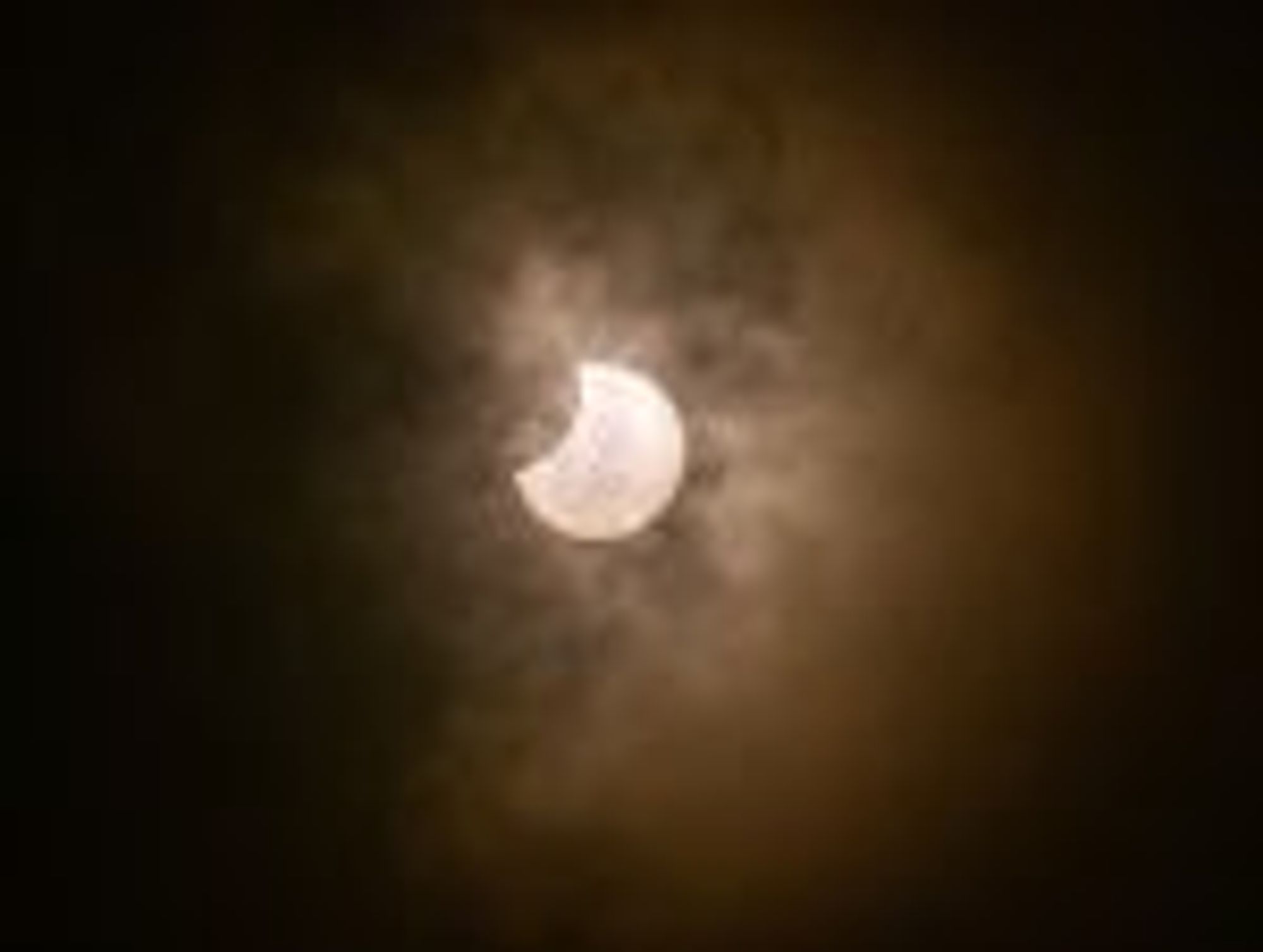 A partial solar eclipse with wispy clouds