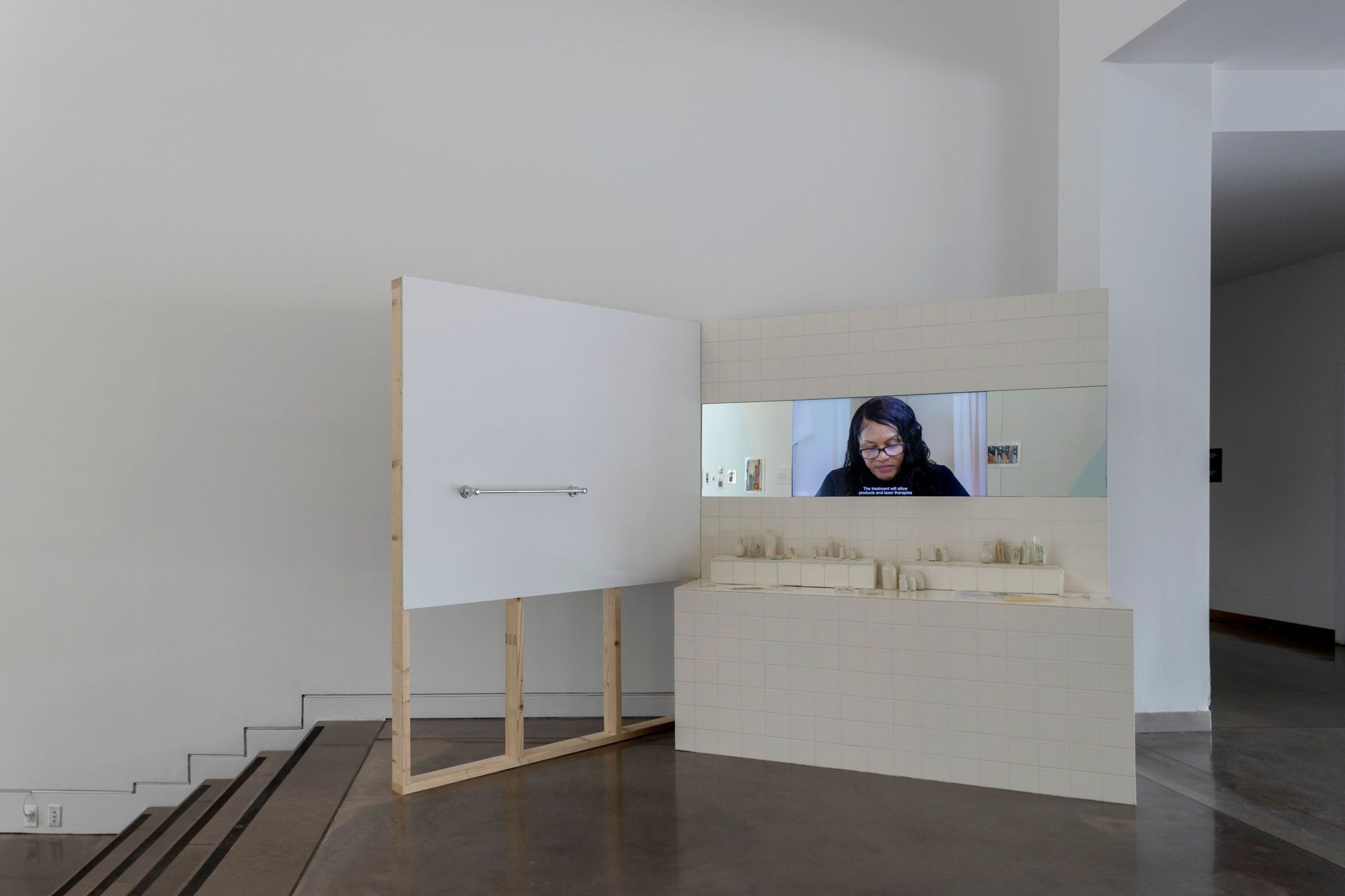 Installation shot of Ilana Harris-Babou, Fine Lines, 2020. Installation with wood, sheetrock, tile, grout, glass, mirror, inkjet print, resin, ceramic sculpture, flatscreen monitor and single-channel HD video, sound, 11 minutes, overall dimensions 84 × 137 × 56 inches. Included in "After the Plaster Foundation, or, "Where can we live?,"" Queens Museum, September 16, 2020 - January 17, 2021. Courtesy of Queens Museum. Image: Hal Zhang.